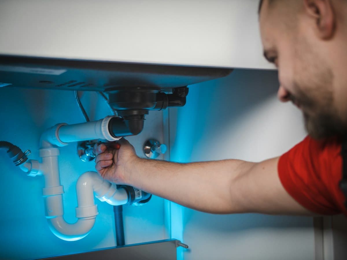 Plumber fitting a pipe under a sink